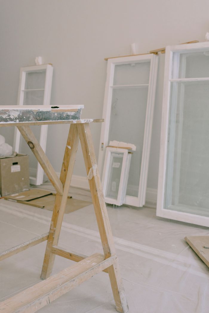 project-03-b Interior of room with wooden workbench and windows removed from hinges with white frame placed near wall in light room during repair works